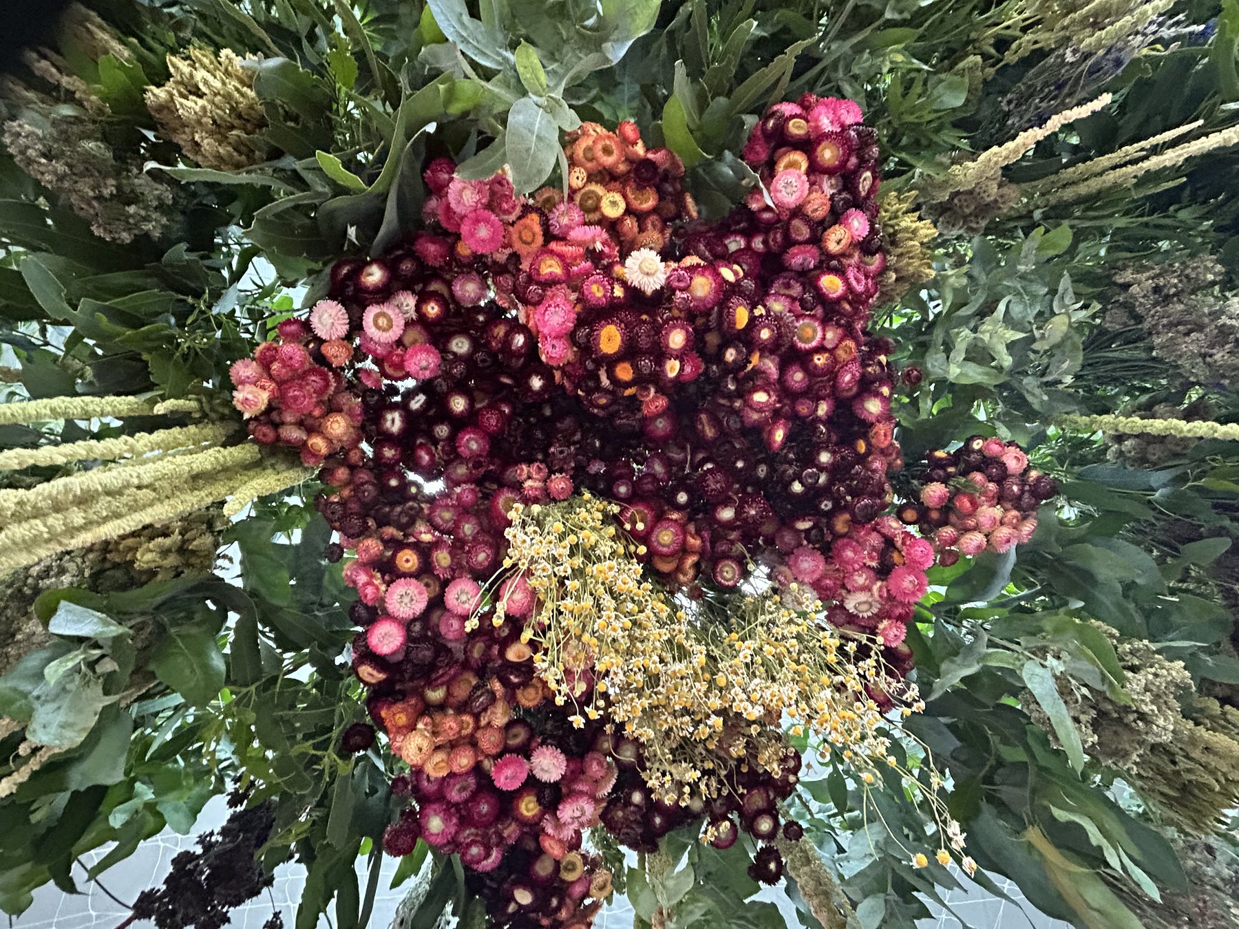 A dense arrangement of strawflower, chamomile and amaranth with foliage